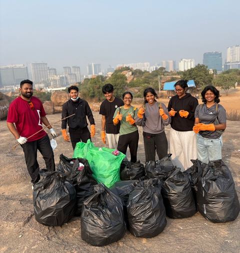 Volunteers with full bags on the rocks, skyline behind