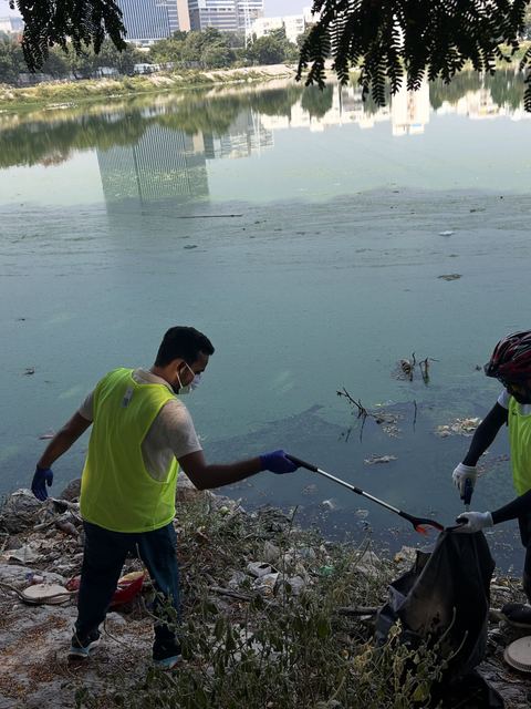 A volunteer reaching into the lake with a litter picker