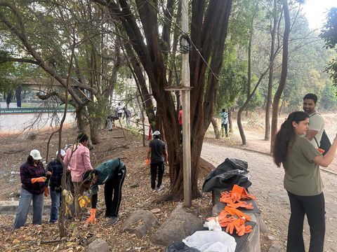 Volunteers picking up trash under the trees at Nerella Lake